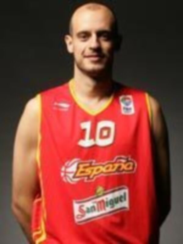 Un jugador de baloncesto con el número 10 y la camiseta de España, posando frente a un fondo negro.
