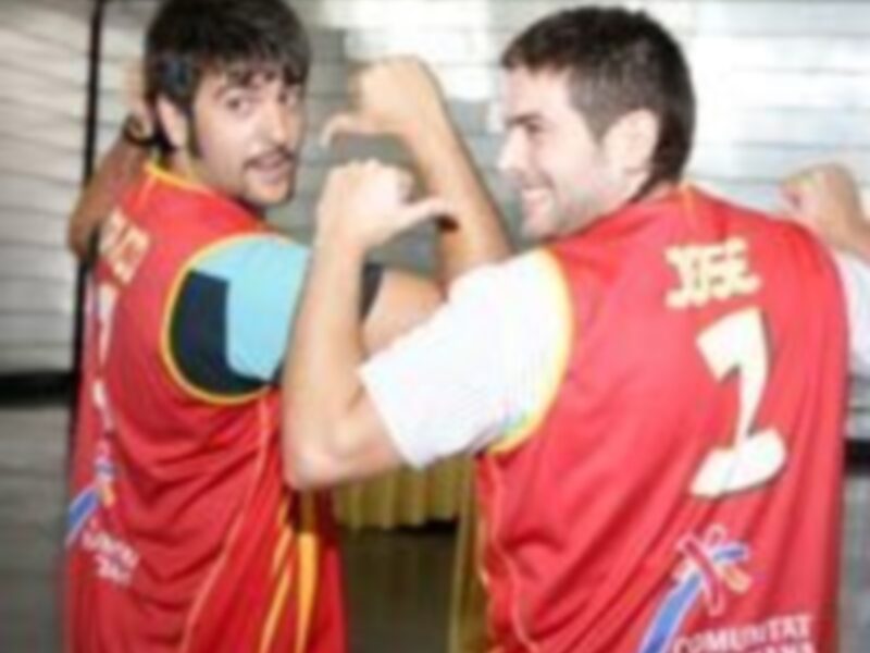 Dos jugadores de baloncesto celebran una victoria, uno con un jersey rojo y otro con blanco, ambos sonrientes.
