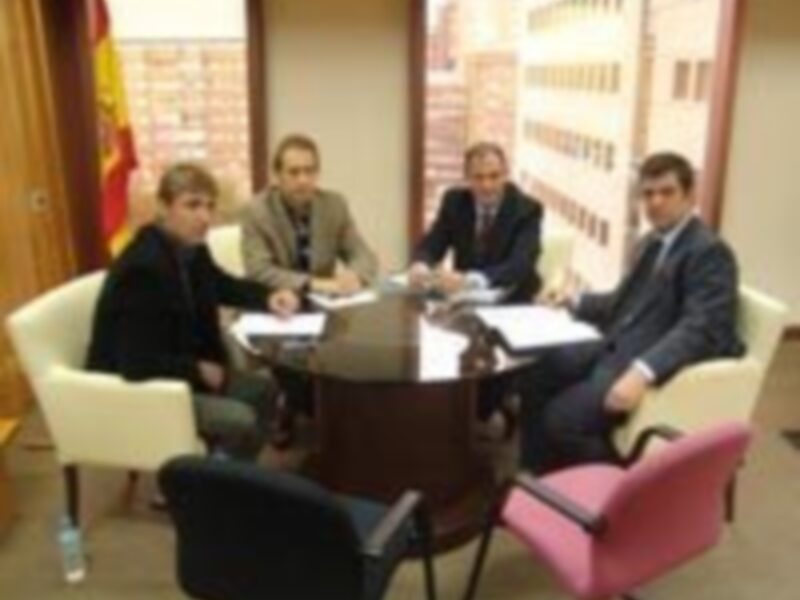 Una reunión en una oficina con sillas rojas, un escritorio y una bandera.