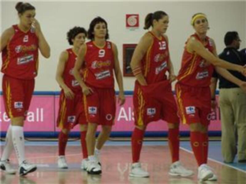 Equipo femenino de baloncesto en acción, vestidos con uniformes rojos y amarillos.