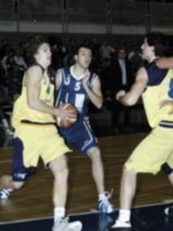 Un jugador en azul y amarillo disputa un balón con otro jugador de la misma equipación. El fondo muestra a varios espectadores en el estadio.