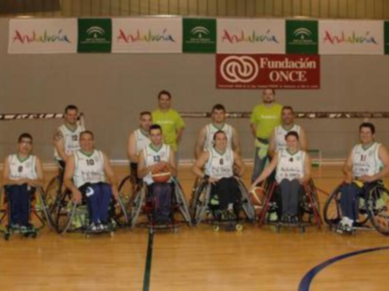 Equipo de baloncesto en silla de ruedas posando en una cancha deportiva.