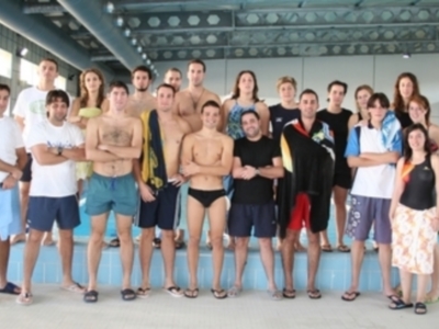 Estudiantes posando en una piscina, algunos con bañadores y otros con camisetas.