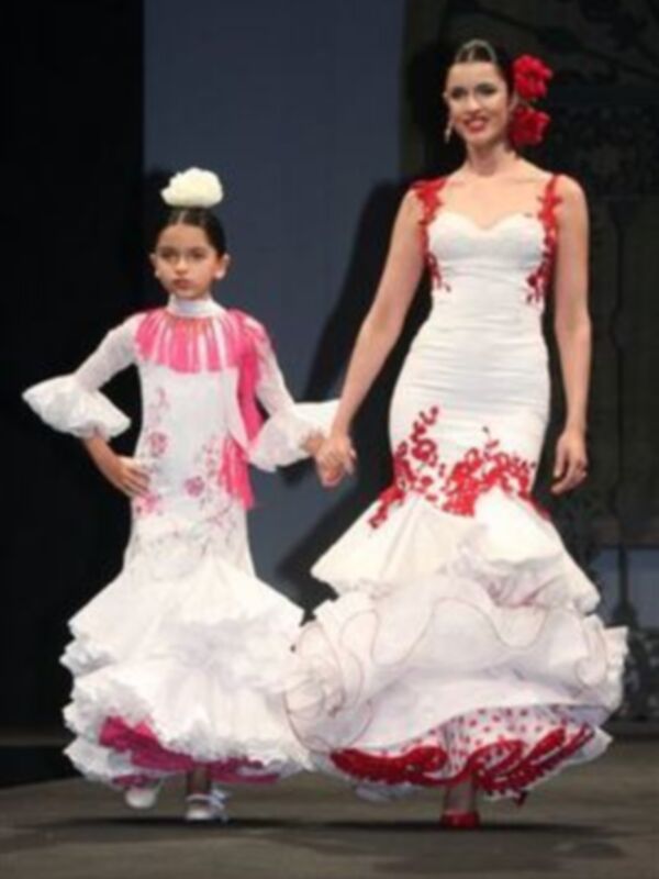 Modelos presentan vestidos tradicionales españoles en una pasarela de moda.