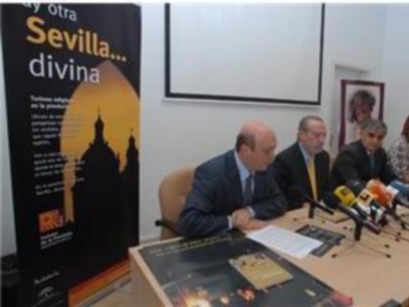 Presentación oficial del libro "Sevilla... divina" en Sevilla. Miembros de la organización se encuentran sentados frente a una mesa con micrófonos y un cartel promocional.