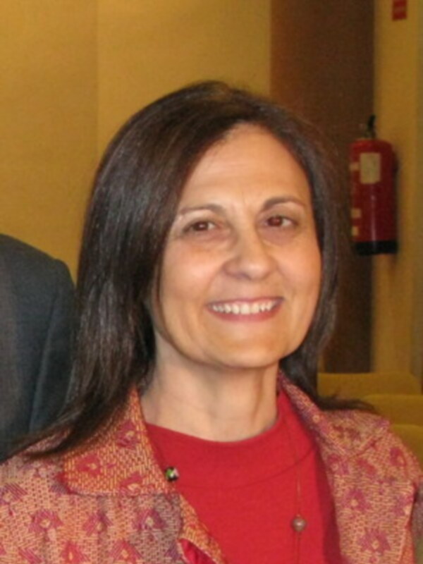 Una mujer sonriendo con una chaqueta roja y un fondo amarillo.