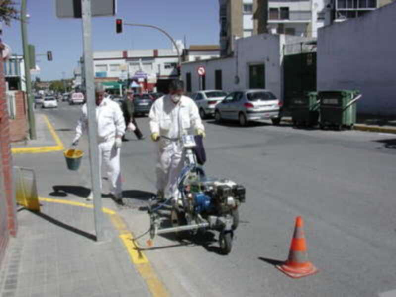Trabajadores pintando una calle con equipo de pintura.
