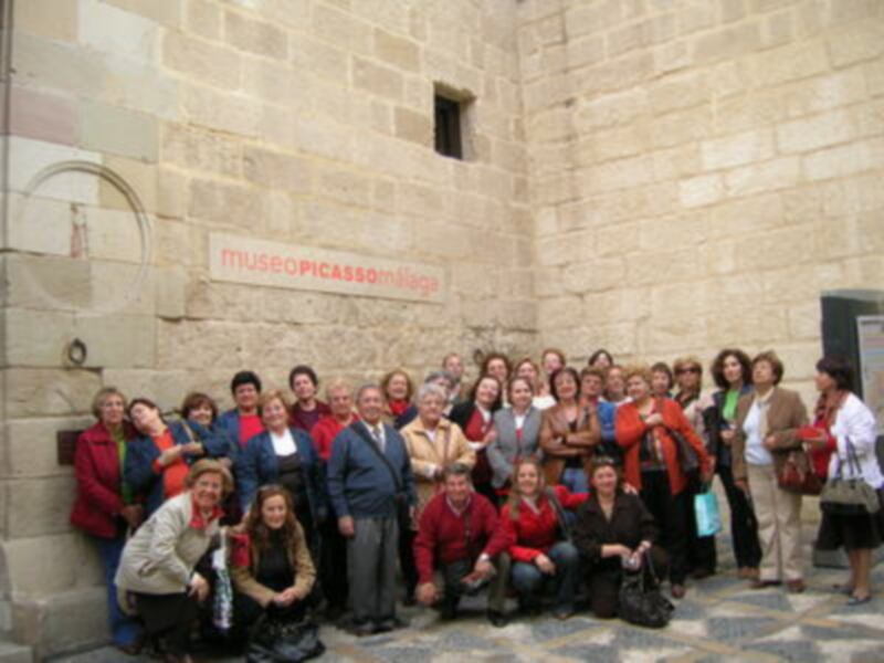 Grupo de personas frente a la entrada del Museo Picasso, con una pared de ladrillo y un cartel que dice "Museo Picasso".