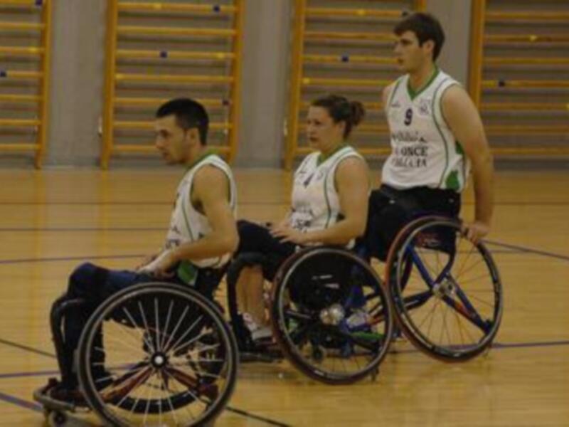Jugadores de baloncesto en silla de ruedas en un partido en una cancha deportiva.