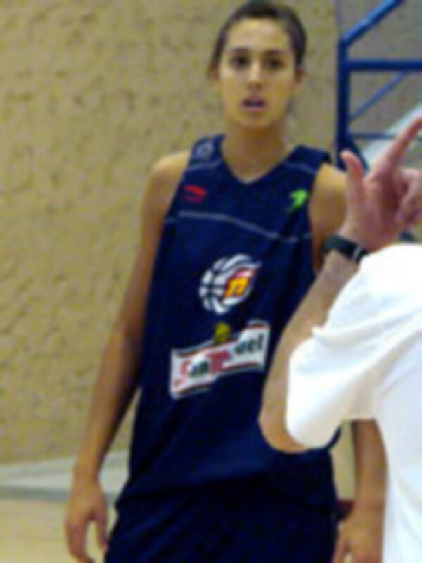 Joven jugando baloncesto en un gimnasio, con una camiseta azul y un número visible.