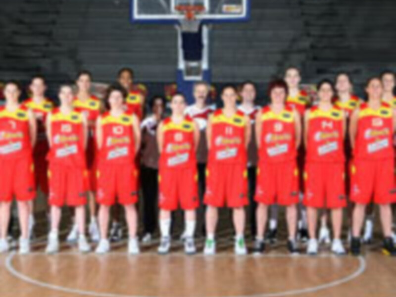 Equipo femenino de baloncesto en uniforme rojo y amarillo, posando para la foto oficial.