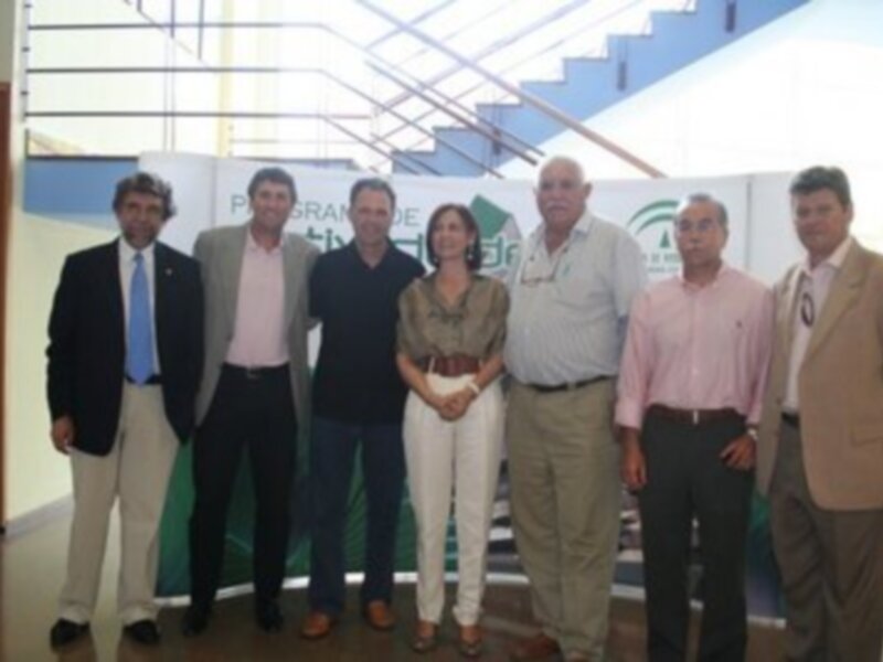 Grupo de personas posando en una presentación oficial, con un fondo que incluye elementos como un panel informativo y escaleras.