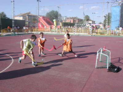 Niños jugando hockey en un campo de juego al aire libre.