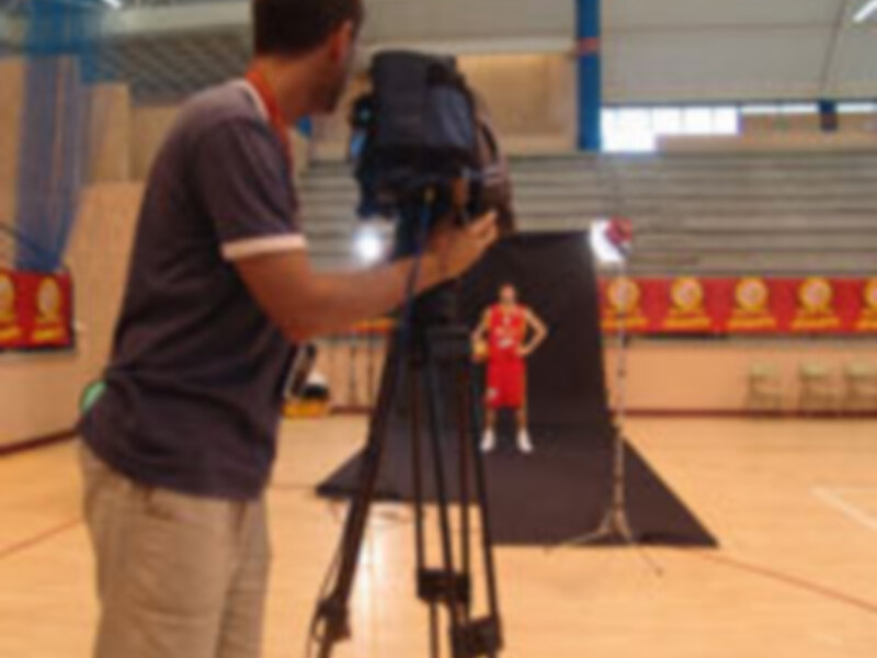 Un hombre filma a un atleta en una cancha de baloncesto.