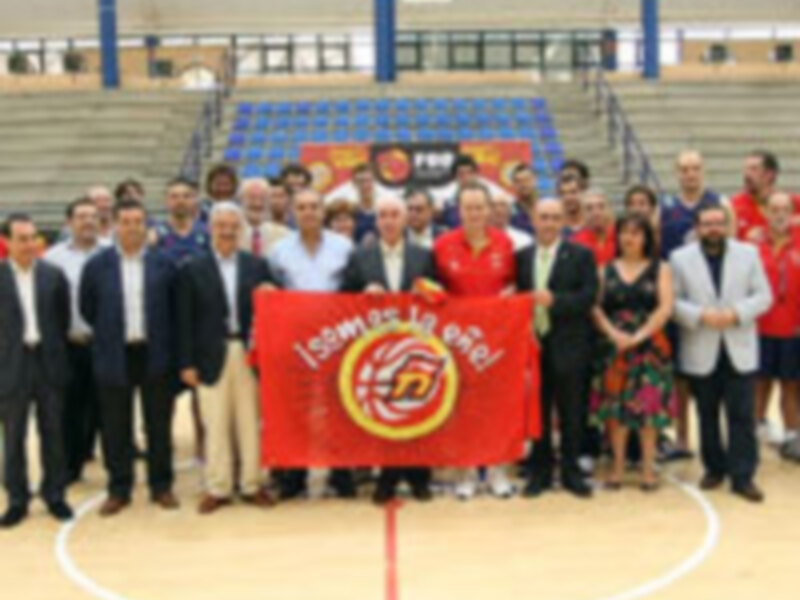 Equipo de baloncesto celebrando con una bandera en el campo de juego.