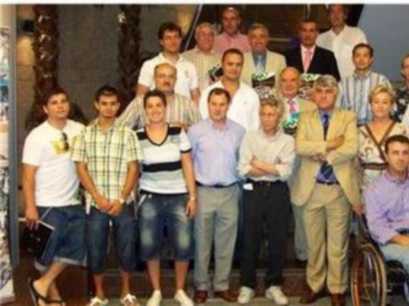 Una imagen de un grupo de personas, incluyendo a un hombre en silla de ruedas, posando para una foto.