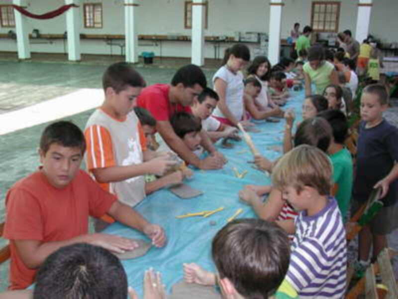 Niños en una reunión comunitaria, sentados a mesas y participando activamente.