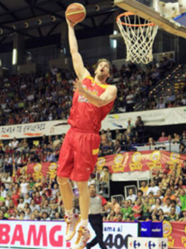 Un jugador de baloncesto en acción, saltando para hacer un dunk. El jugador lleva una camiseta roja con el número 1 y está en un estadio lleno de espectadores. La imagen muestra una jugada intensa en un partido de baloncesto profesional.