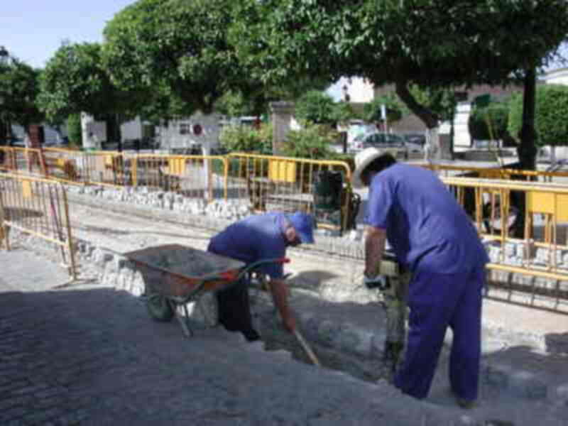 Trabajadores en un proyecto de construcción, colocando baldosas en una calle.