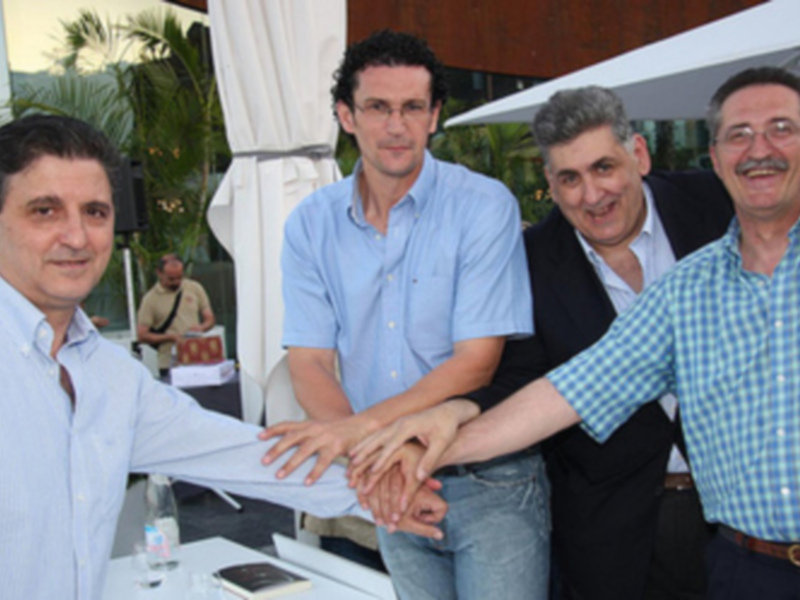 Grupo de hombres sonriendo y sosteniendo una hoja de papel juntos.