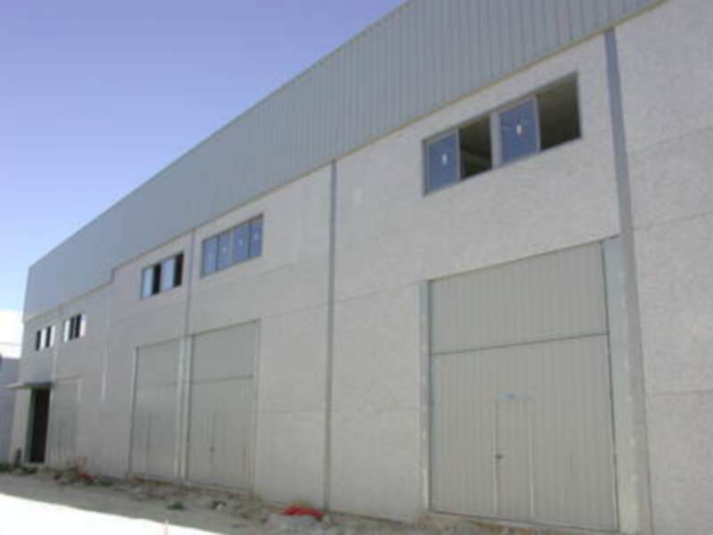 Un edificio industrial con múltiples ventanas y puertas de acceso.