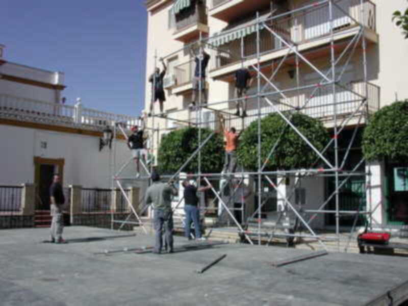 Trabajadores en una plataforma de construcción, trabajando en un edificio con balcones.