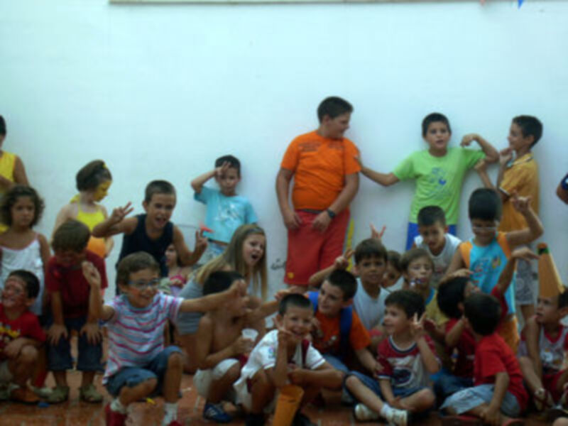 Niños sonrientes en una escuela, algunos con uniforme escolar y otros con camisetas de colores.