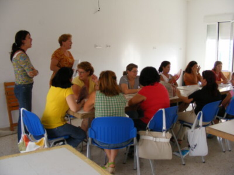 Una clase de yoga en un aula con mujeres sentadas y una instructora.