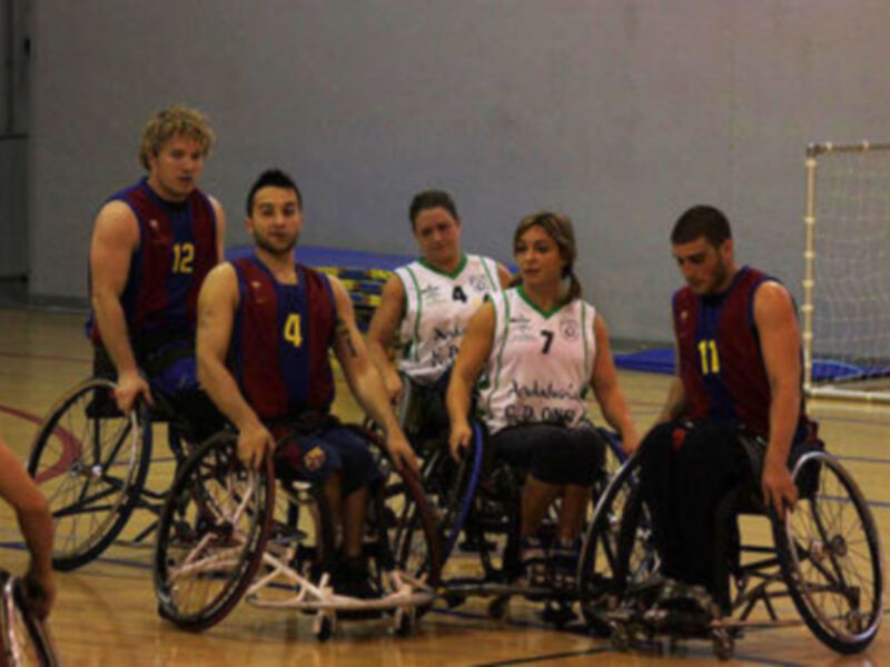Equipo de baloncesto en silla de ruedas reunido en el centro del campo de juego.