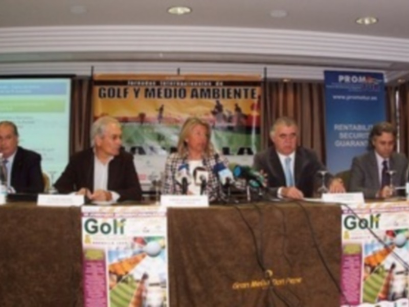 Conferencia sobre Golf y Medio Ambiente en una sala de conferencias con cuatro personas sentadas detrás de un mostrador.