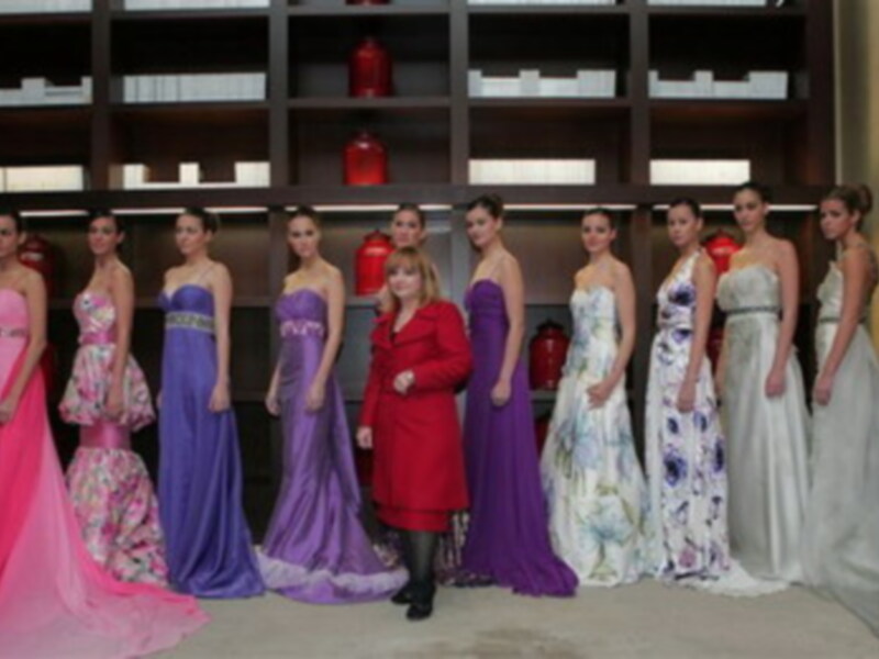 Una fila de modelos posando en diferentes vestidos de fiesta, incluyendo un vestido de color rojo, otro de color azul y otro de color blanco.