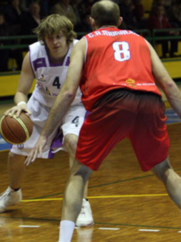 Un jugador de baloncesto en acción, con el número 4 en su camiseta, intentando controlar el balón mientras es seguido por otro jugador con el número 8 en su camiseta roja.