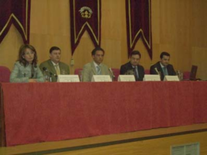 Una mesa con cuatro personas sentadas en una conferencia, detrás de ellos hay banderas y un cartel.