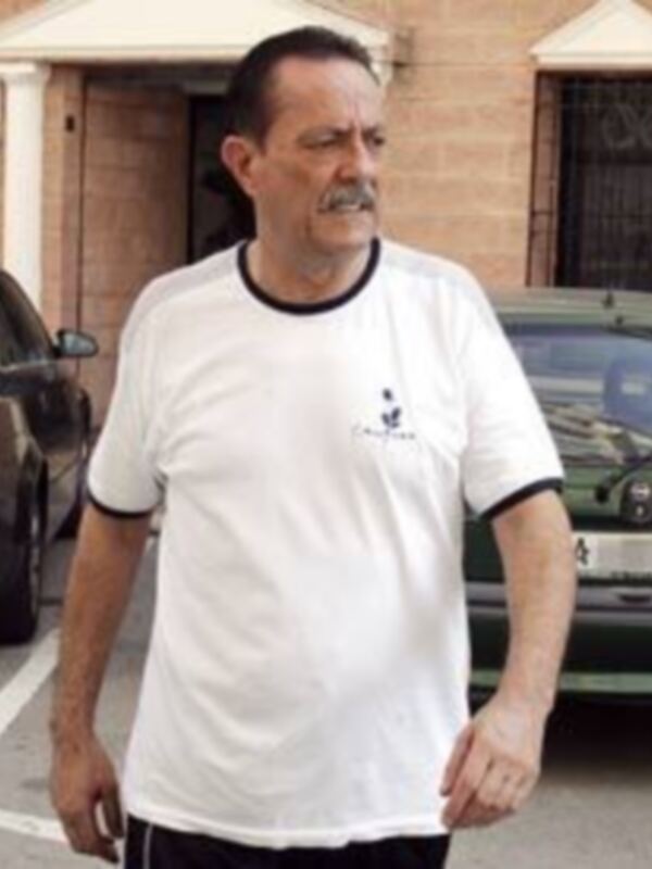 Hombre con camiseta blanca caminando en una calle urbana.