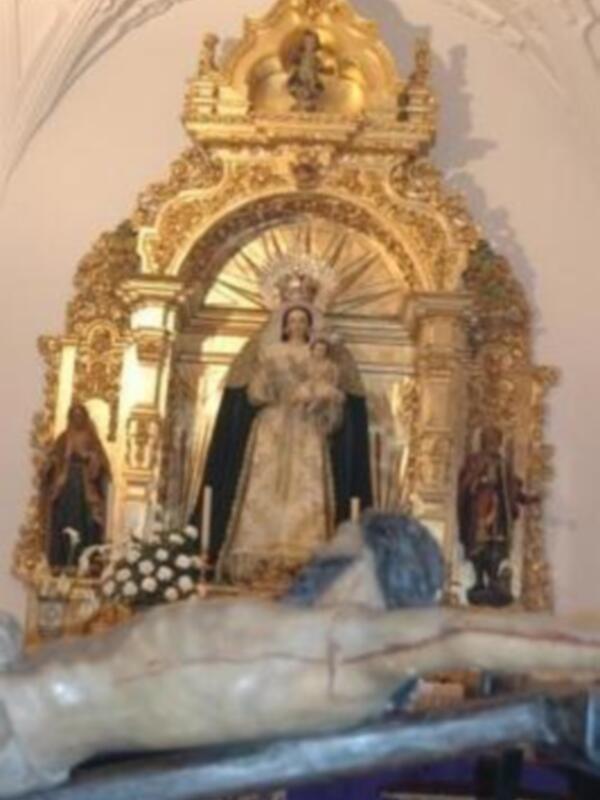 Una escultura de Cristo crucificado en la parte inferior, con un altar dorado y una imagen religiosa central.