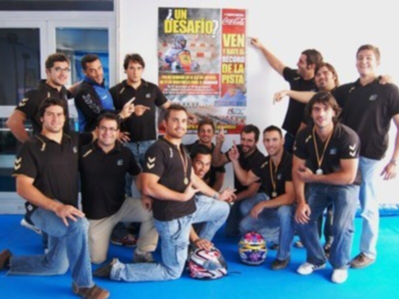 Equipo de fútbol celebrando junto a un cartel promocional.