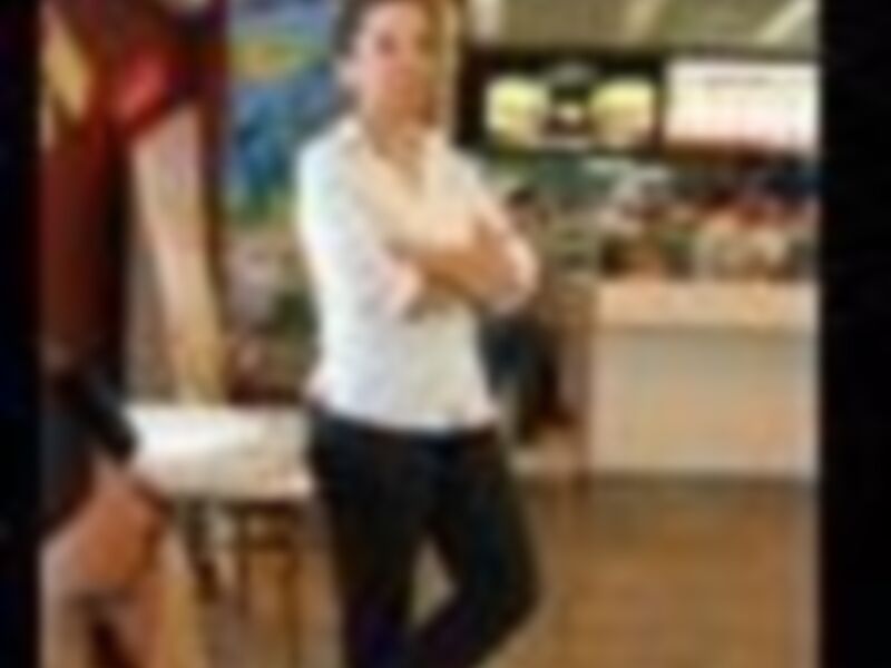 Una persona en una tienda de ropa, posando con una camiseta blanca y pantalones negros.