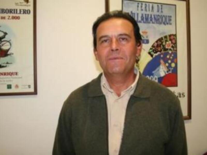 Un hombre en una oficina con carteles de la Feria de Salamanca en el fondo.