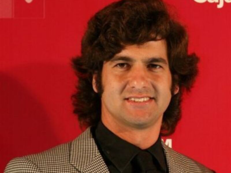 Un hombre con cabello largo y una sonrisa amistosa.