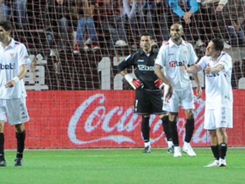 Jugadores de fútbol en el campo, con una publicidad de Coca-Cola en el fondo.