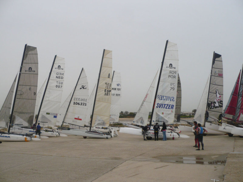 Barcos con velas en una pista de regatas, preparándose para la competencia.
