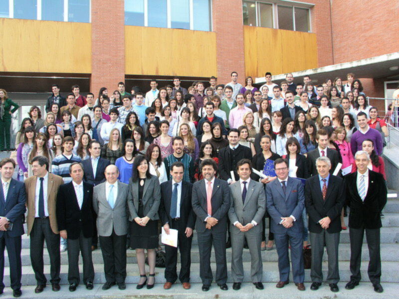 Grande grupo de personas posando para una foto grupal en un evento institucional frente a un edificio moderno.