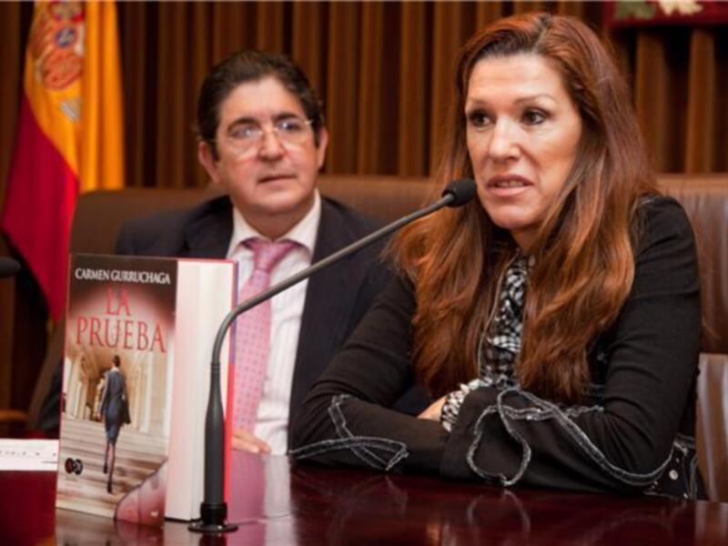 Carmen Guiruchaga en una conferencia de prensa, con un libro titulado 'La Prueba' en el frente de la mesa.