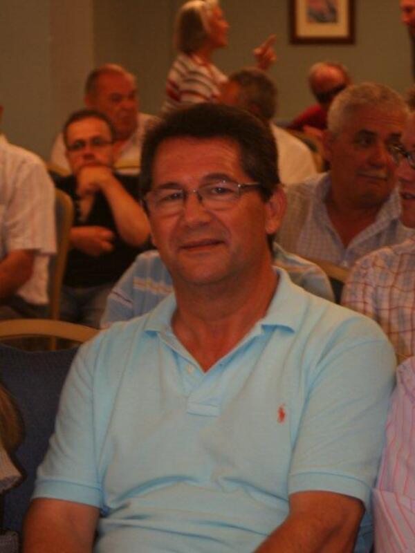 Hombre en polo azul claro asistiendo a una reunión o conferencia en un auditorio.
