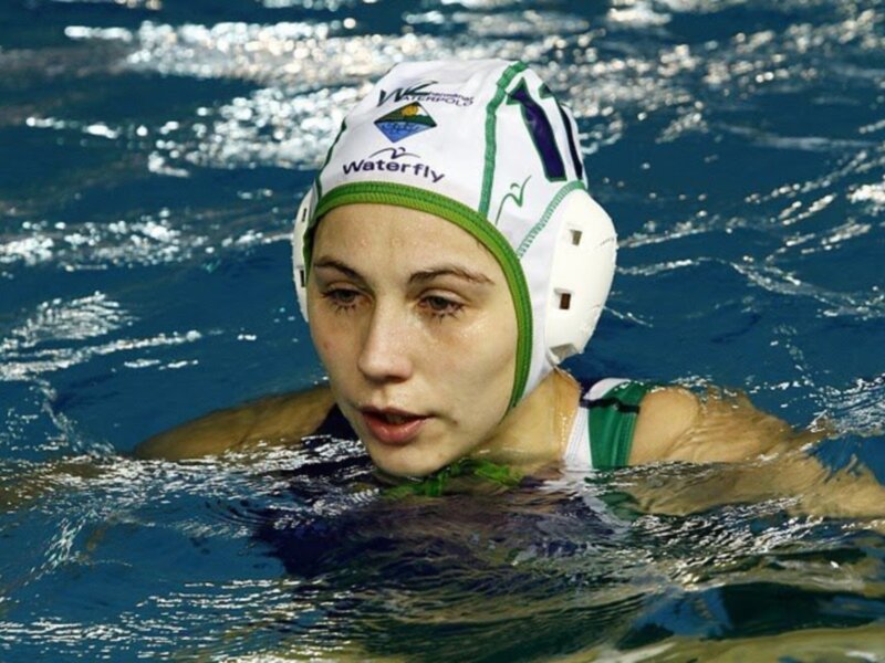 Una jugadora de waterpolo con un casco de protección en el agua.