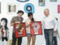 Tres personas celebran con discos de oro en un ambiente de oficina decorado con carteles musicales.