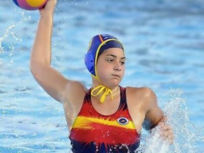 Joven jugadora de waterpolo en acción, lanzando el balón en una piscina.