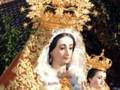 Imagen de una Virgen con un niño en sus brazos, vestida con trajes tradicionales y coronada de oro.