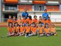 Equipo infantil de hockey sobre césped posando en un estadio deportivo.