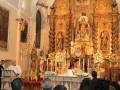 Imagen de una iglesia con un altar dorado y estatuas, donde se celebra una ceremonia religiosa.